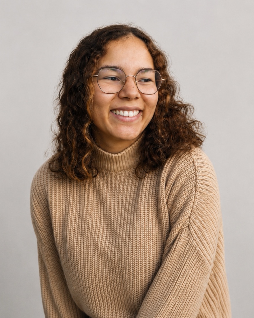 Portrait d'Anyssa Lecomte, souriante, en pull beige, sur fond gris clair